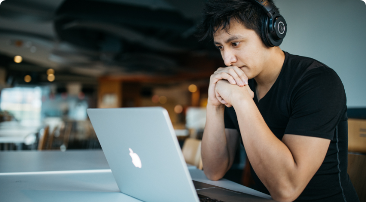 Asian man sitting at desk working on Apple Macbook computer