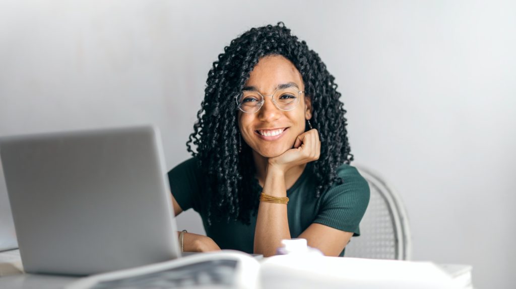 Woman sitting at work desk and resting chin on hand for photo